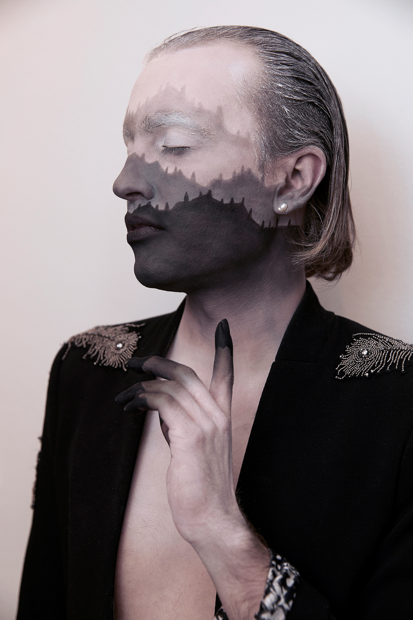 Jesse Clark posing with his hand in front of his chest with black and white facepaint that resembles a mountain range against a white background
